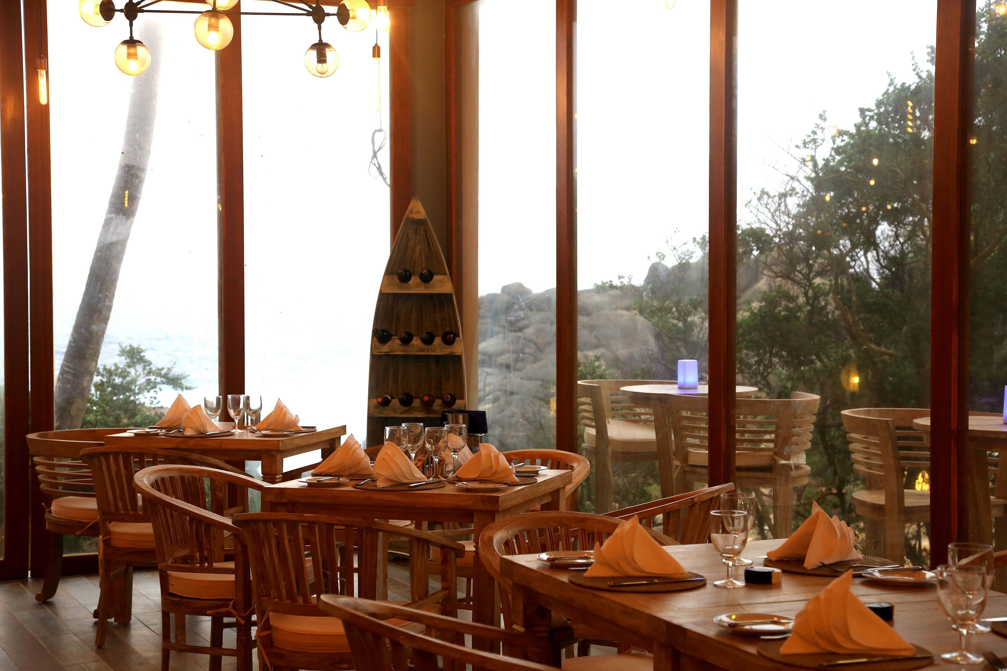 A restaurant with wooden furniture and large windows offering a view of the outdoors.
