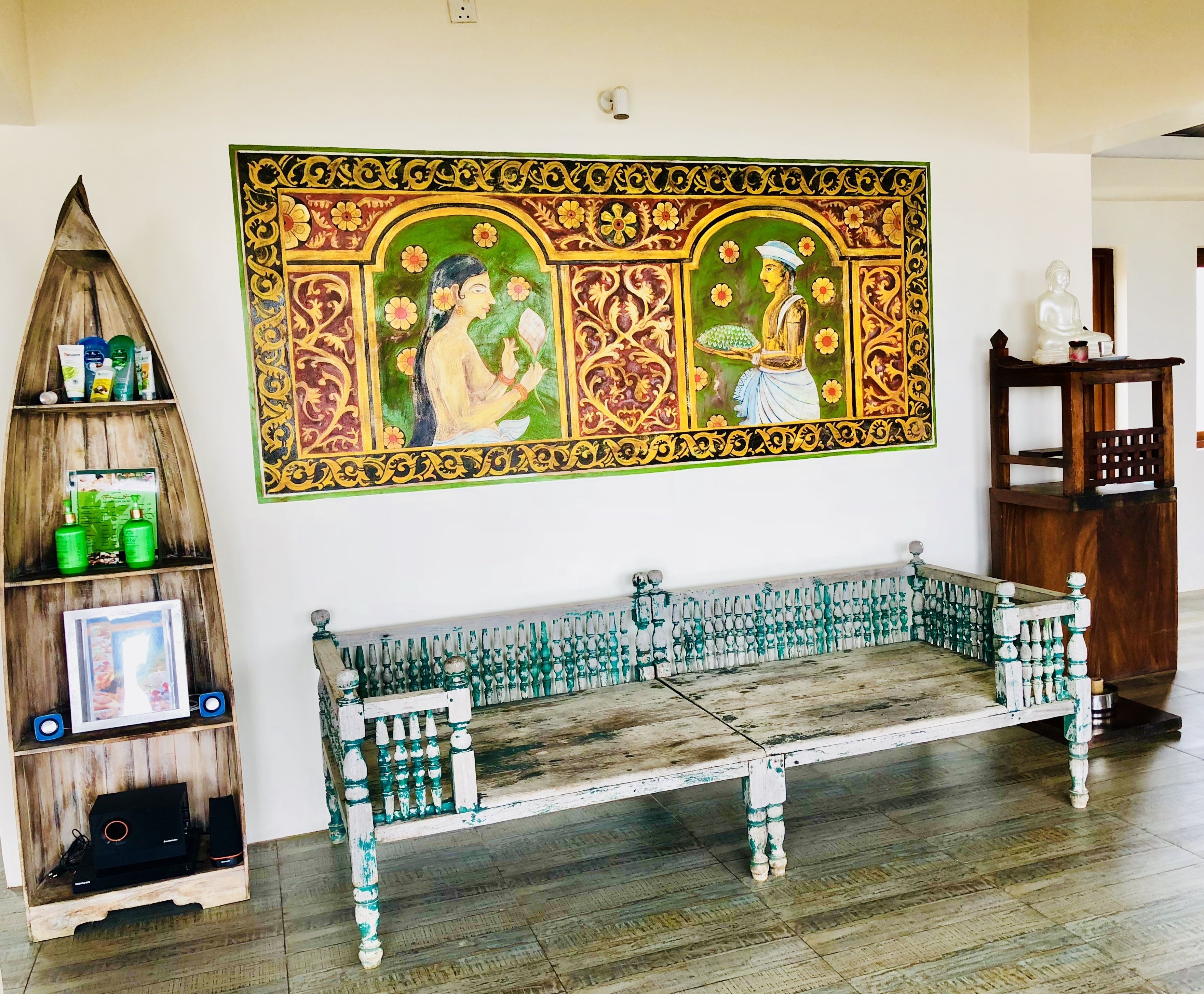 Una habitación con un banco de madera, un estante con artículos de aseo y un cuadro decorativo grande en la pared.
