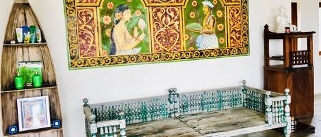 Una habitación con un banco de madera, un estante con artículos de aseo y un cuadro decorativo grande en la pared.