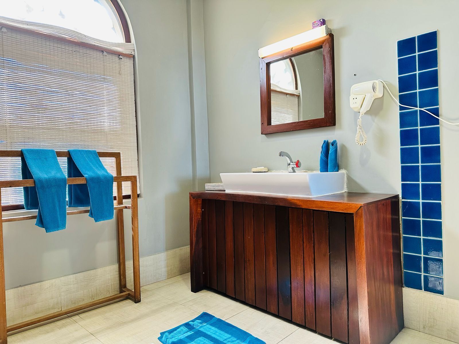 A bathroom with a wooden vanity, a sink, a mirror, and a towel rack.