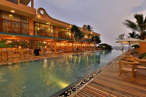 Un hotel con zona de piscina, terraza de madera y mobiliario exterior.