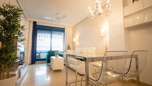 Ein modernes Wohnzimmer mit Essbereich, einer Kristallleuchtre und einem großen Fenster mit Vorhängen.