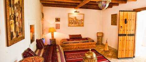 A traditional room with a wooden ceiling, a bed with red and white striped bedding, a wooden chest, and a colorful rug.