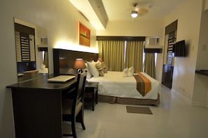 A hotel room with a bed, desk, chair, and a television.