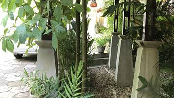 Un espace extérieur abrité, doté d’un chemin en pierre, de plantes en pot et d’une lanterne suspendue.
