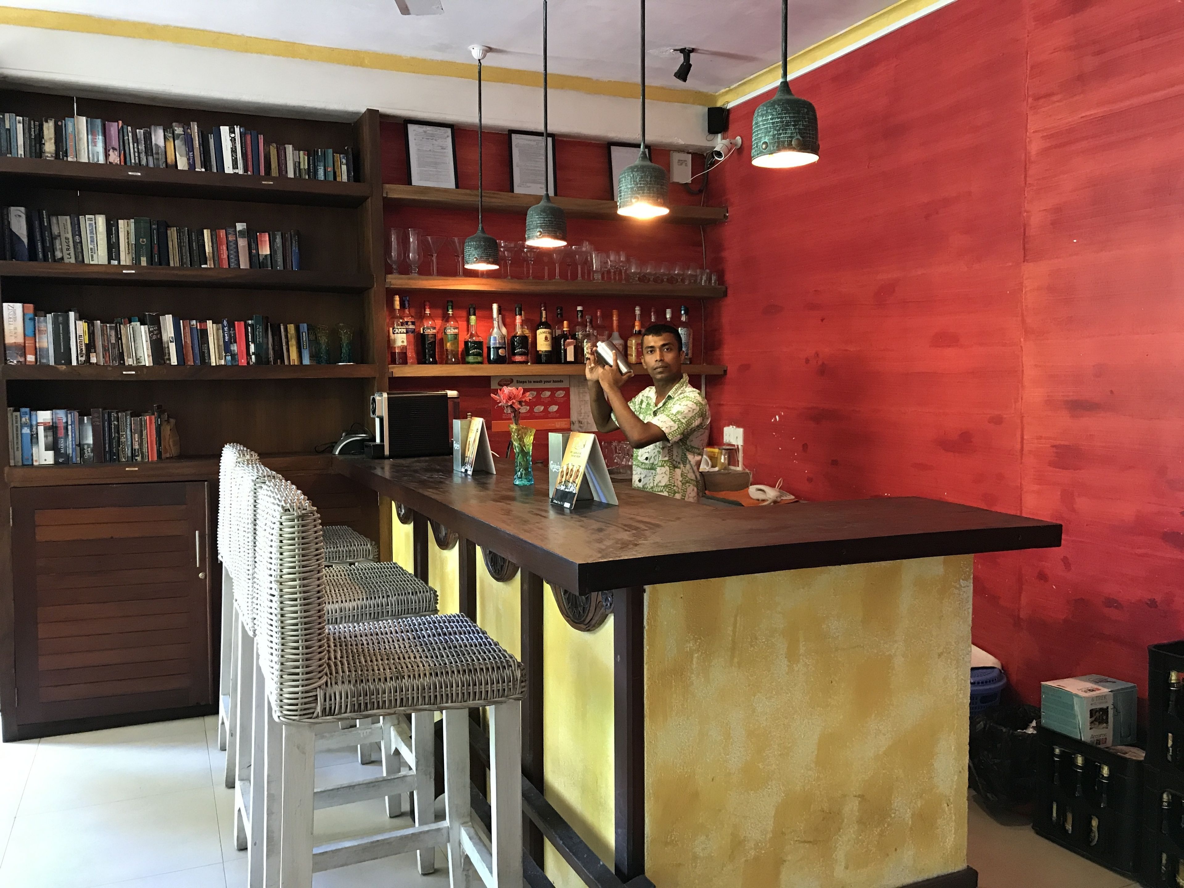 Zona de bar con mostrador, taburetes y estanterías llenas de botellas.