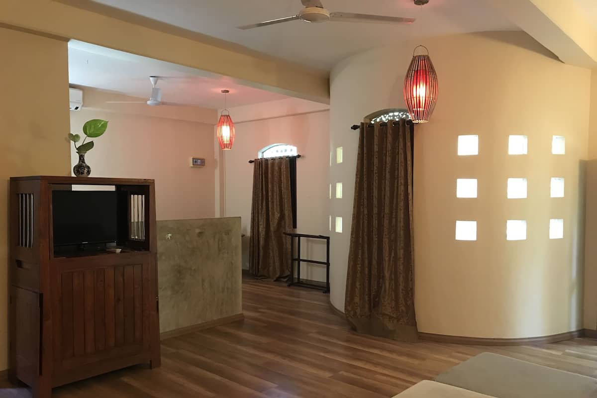 A modern living room with a wooden entertainment unit, a sofa, and a ceiling fan.