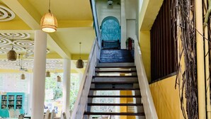 Un escalier surmonté d’une porte bleue, entouré de murs jaunes et de colonnes blanches.