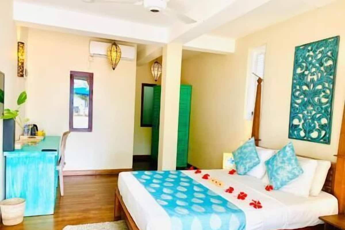 Quarto com cama, mesa de cabeceira e escrivaninha com cadeira.
