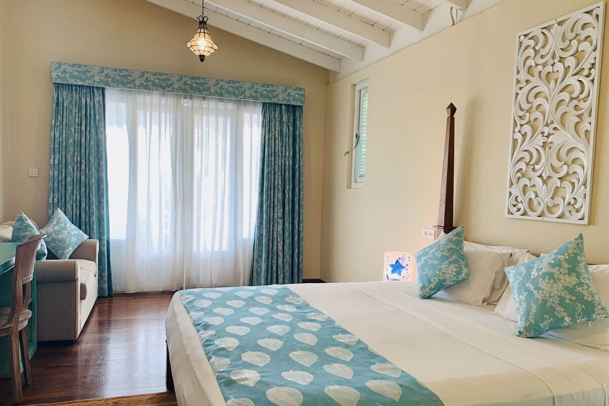 Une chambre à coucher avec un lit, un bureau et une chaise, ainsi qu’une fenêtre et des rideaux.