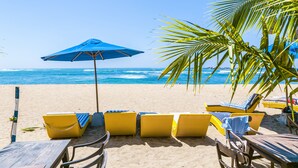 Une plage avec des chaises longues jaunes et un parasol bleu.