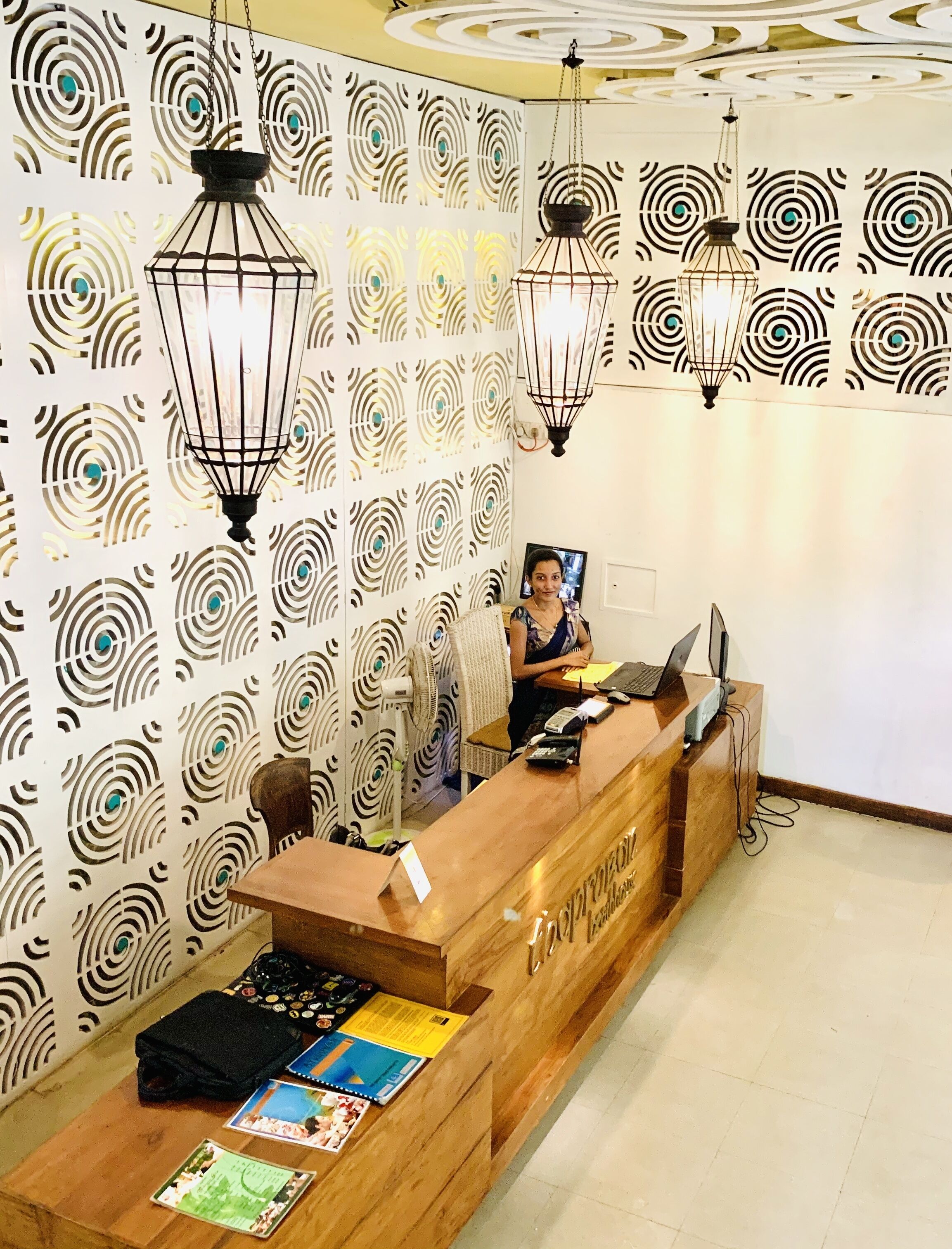 Una recepción con un muro estampado, mostrador de madera y lámparas colgantes.