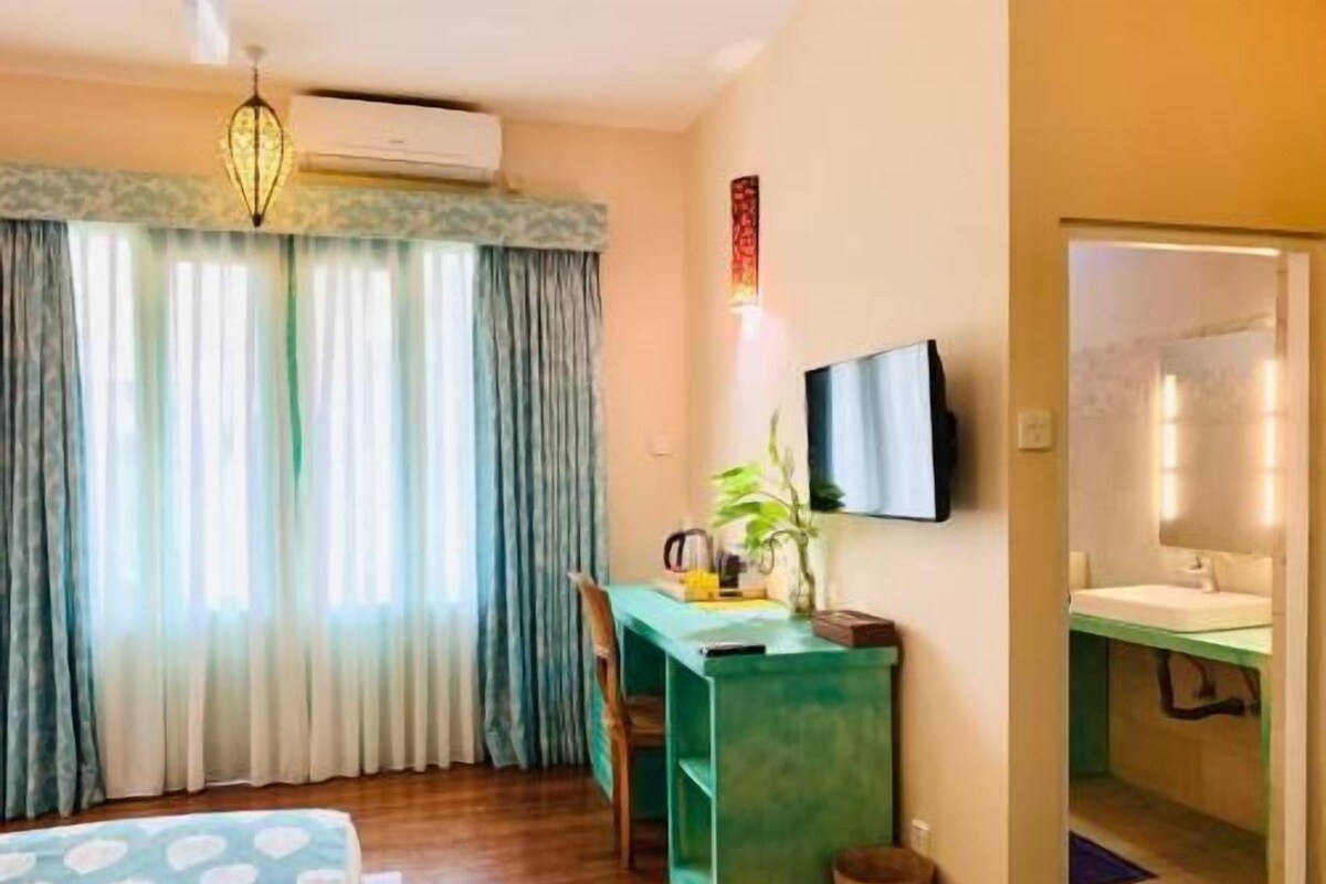 Een hotelkamer met een bed, bureau, stoel, televisie en een badkamer.