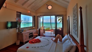 Une chambre avec un lit, un bureau, une télévision et un balcon donnant sur l’océan.