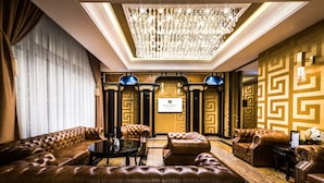 A luxurious lobby with a grand chandelier, plush leather sofas, and a classic design.