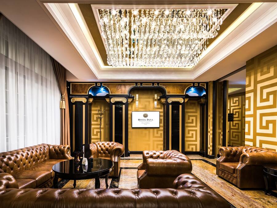 A luxurious lobby with a grand chandelier, plush leather sofas, and a classic design.
