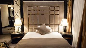 A hotel room with a large bed, two bedside lamps, a headboard with a grid pattern, and a patterned rug.