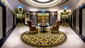 A hotel lobby with a circular seating area, a chandelier, and a patterned carpet.