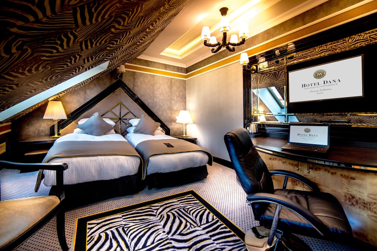 A hotel room with a large bed, two bedside tables, a desk, and a chair.
