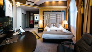 A hotel room with a large bed, a desk with a computer, a chair, and a television.