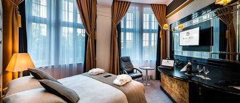 A hotel room with a large bed, a desk, a chair, and a minibar.
