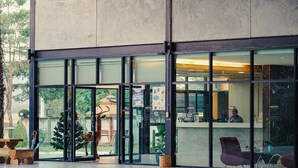 Un edificio moderno con amplias puertas de vidrio, una recepción y zona de estar al aire libre.