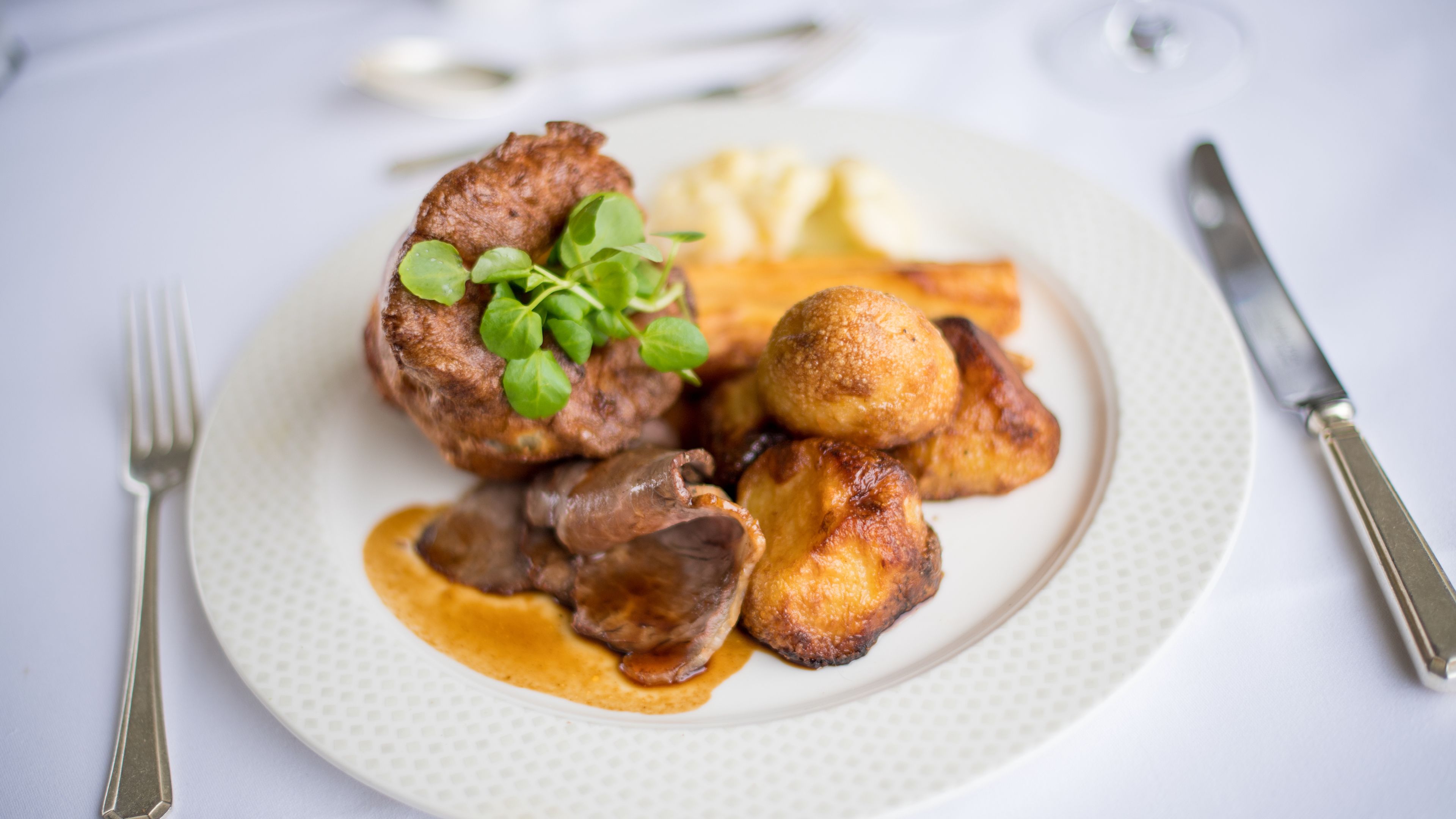 A plate with a steak, roasted potatoes, and a creamy sauce.