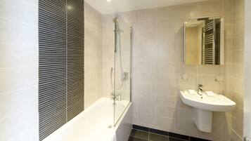 A modern bathroom with a glass-enclosed shower, a white sink, and a large mirror.