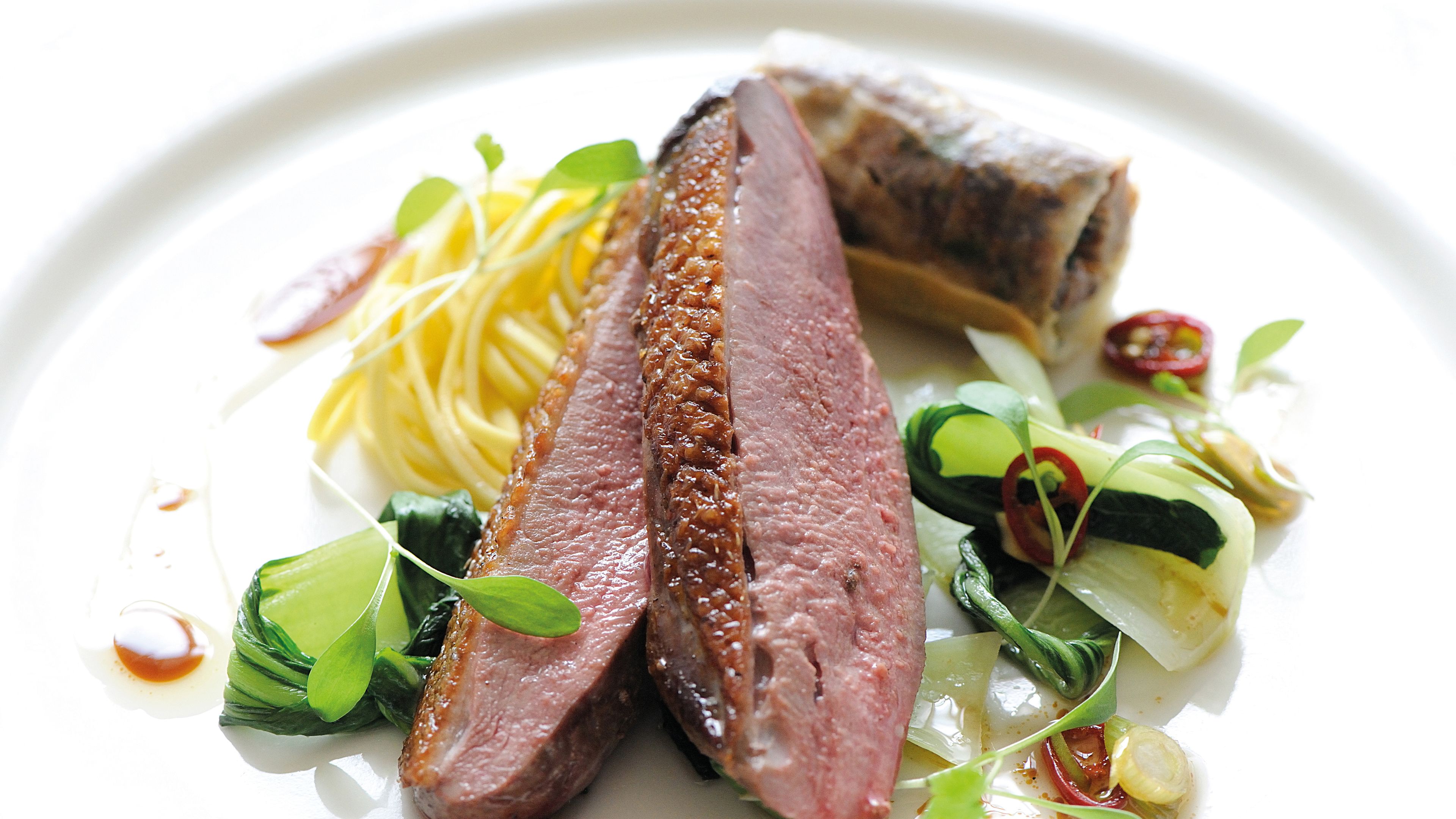 A plate of food with sliced meat, noodles, and vegetables.