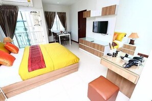 A hotel room with a bed, a desk, a TV, and a window with curtains. - Smart Mansion (Bangkok)