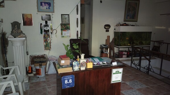 A room with a wooden desk, various items on it, a large fish tank, and a chair.