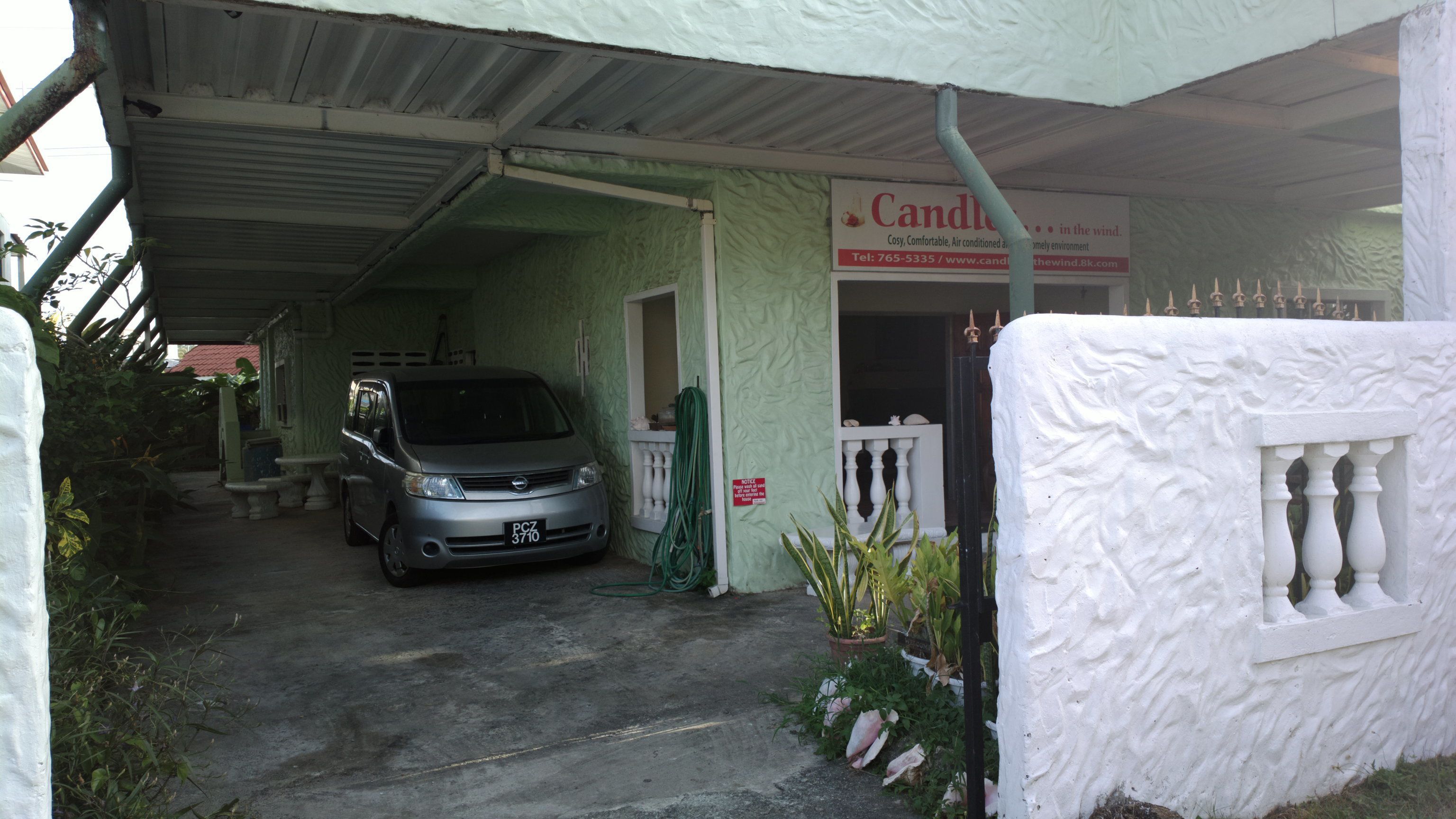 Un bâtiment doté d’une entrée couverte, une voiture garée et une enseigne publicitaire pour une boutique de bougies.
