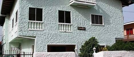 A two-story house with a textured exterior, a balcony on the second floor, and a sign that reads "Candles".