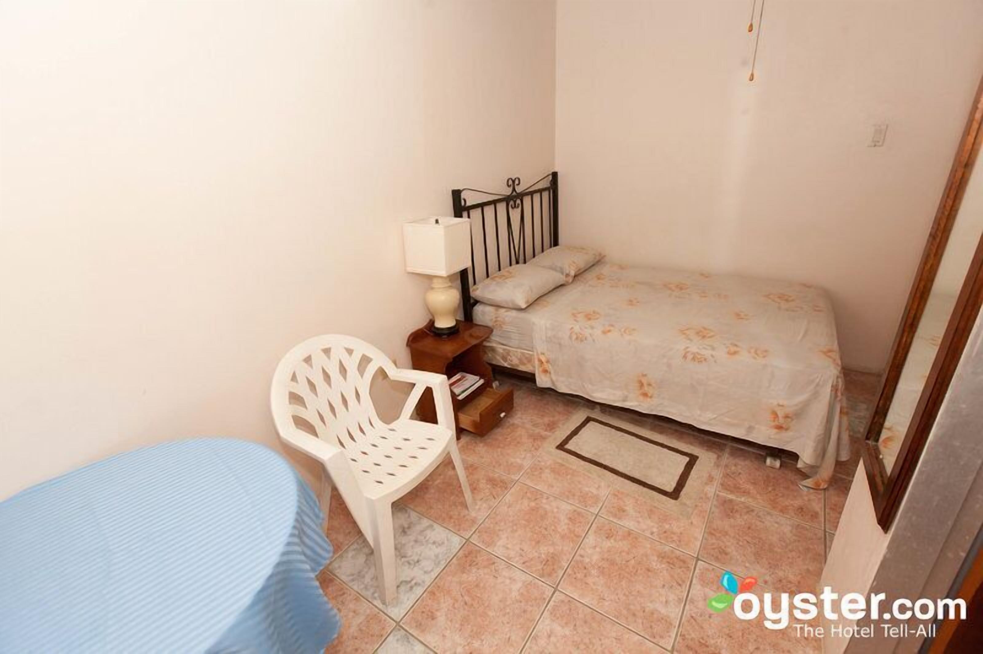 Un dormitorio pequeño con cama, mesita de noche, silla y mesa.