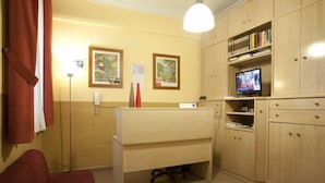 A small, well-lit room with a desk, a television, and a bookshelf. - Hostal Prim (Madrid)