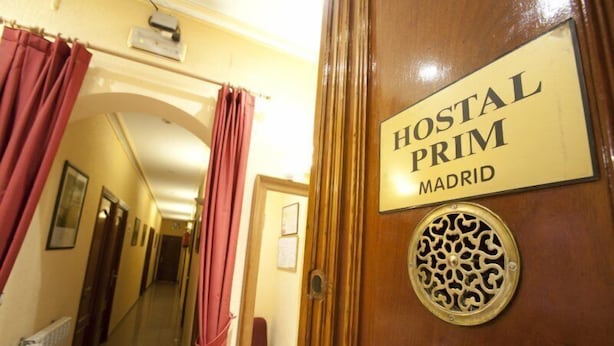 A hallway with a sign reading "HOSTAL PRIM MADRID" on a wooden door. - Hostal Prim (Madrid)
