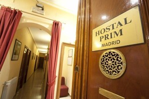 Um corredor com uma placa indicando "HOSTAL PRIM MADRID" em uma porta de madeira.