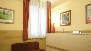 A hotel room with a red sofa, a desk, a window with curtains, and a sign indicating Wi-Fi availability. - Hostal Prim (Madrid)