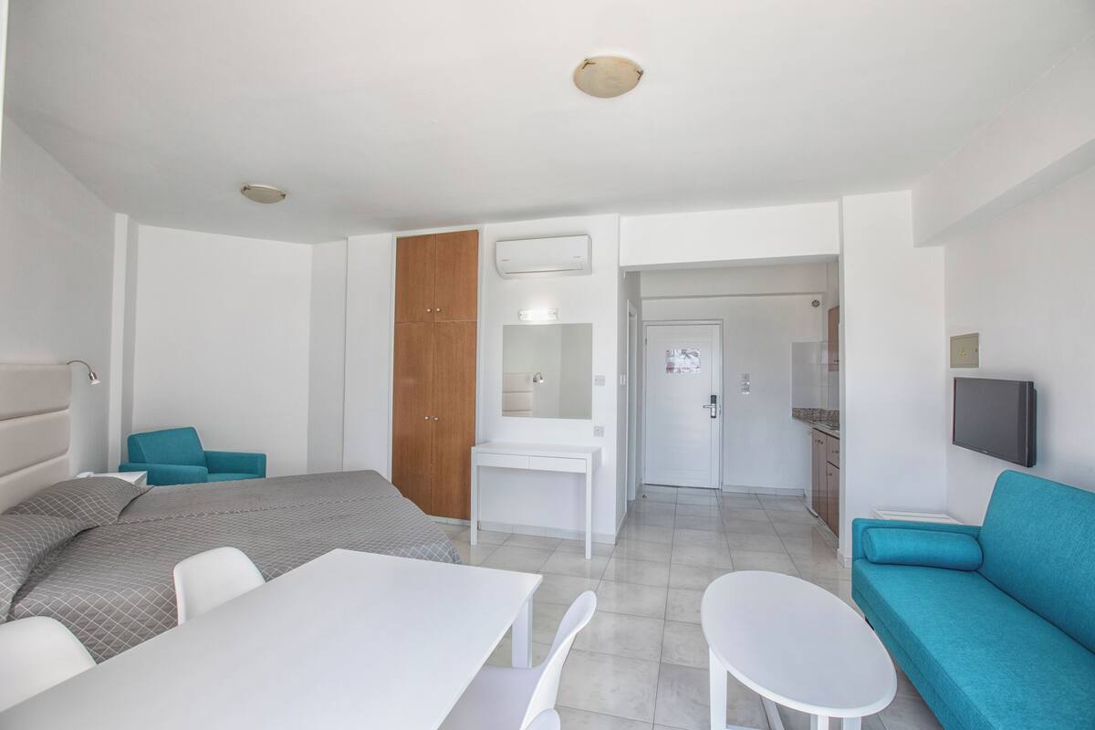 Une chambre d’hôtel moderne équipée d’un lit, d’un bureau, d’une petite table, d’un canapé et d’une télévision.
