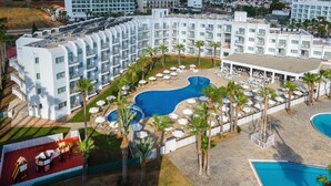A hotel with multiple floors, a central swimming pool, and outdoor seating areas.