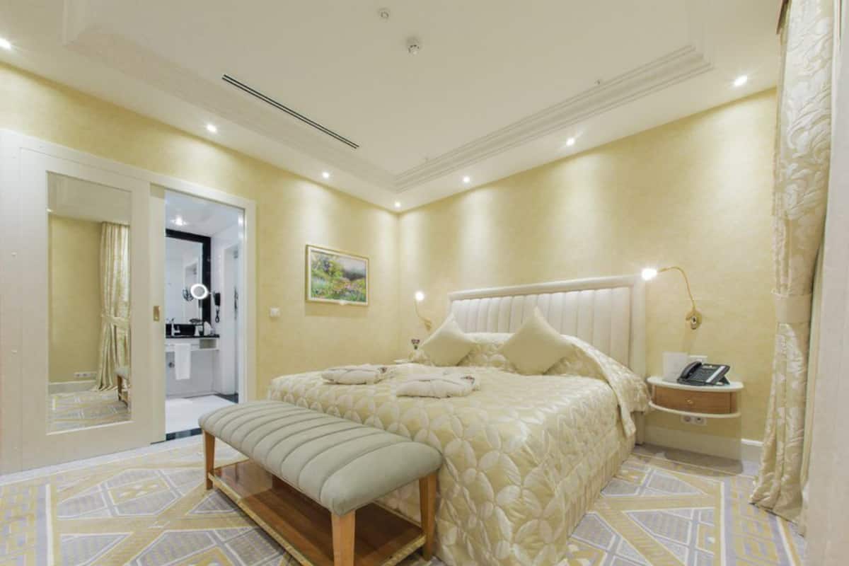 A bedroom with a bed, bench, bedside table, and a mirror.