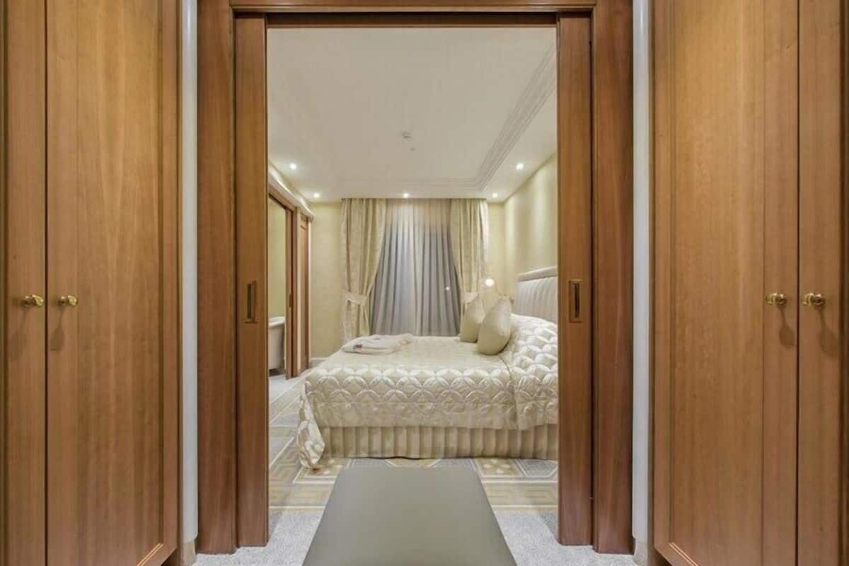 A bedroom with a bed, curtains, and wooden wardrobe doors.