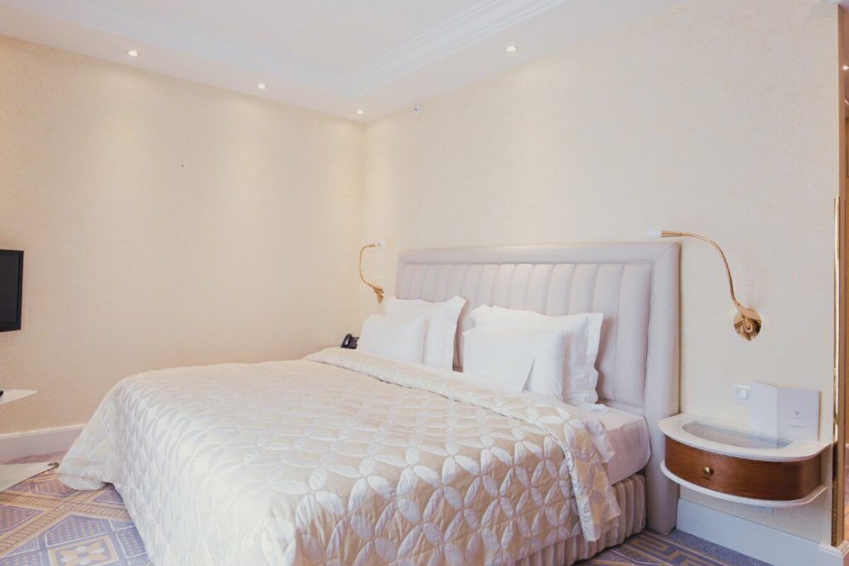 A hotel room with a large bed, a bedside table, and a wall-mounted TV.