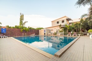 A swimming pool with lounge chairs and a building in the background. - OYO 824 Valida Resort (Pattaya)