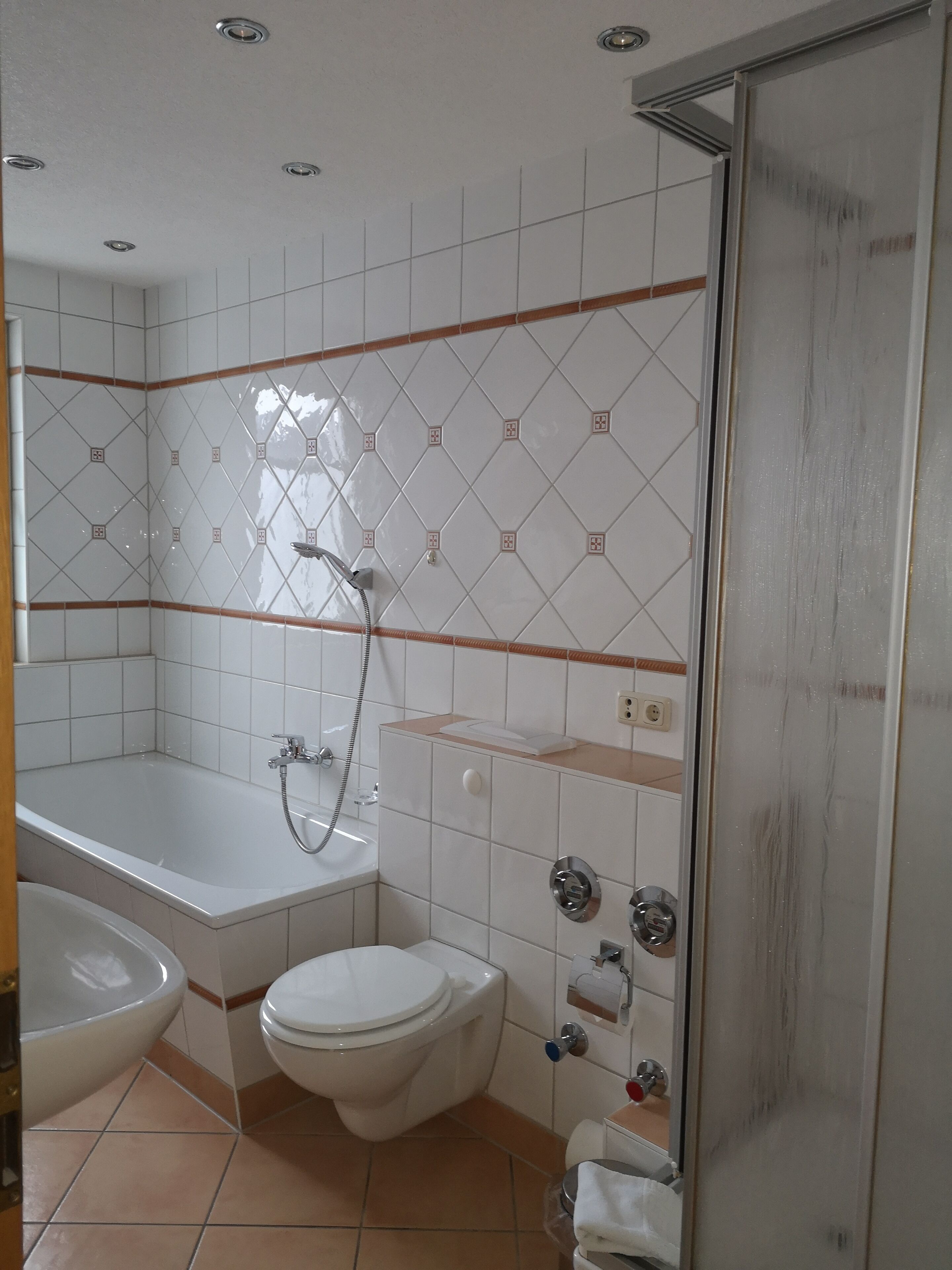 A bathroom with a bathtub, toilet, and shower area.