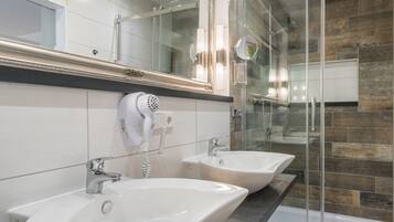 Un baño moderno con dos lavamanos, un espejo grande y una ducha con cerramiento de vidrio.