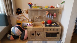 Una cocina de juguete con un fregadero, estufa y diferentes utensilios de cocina.