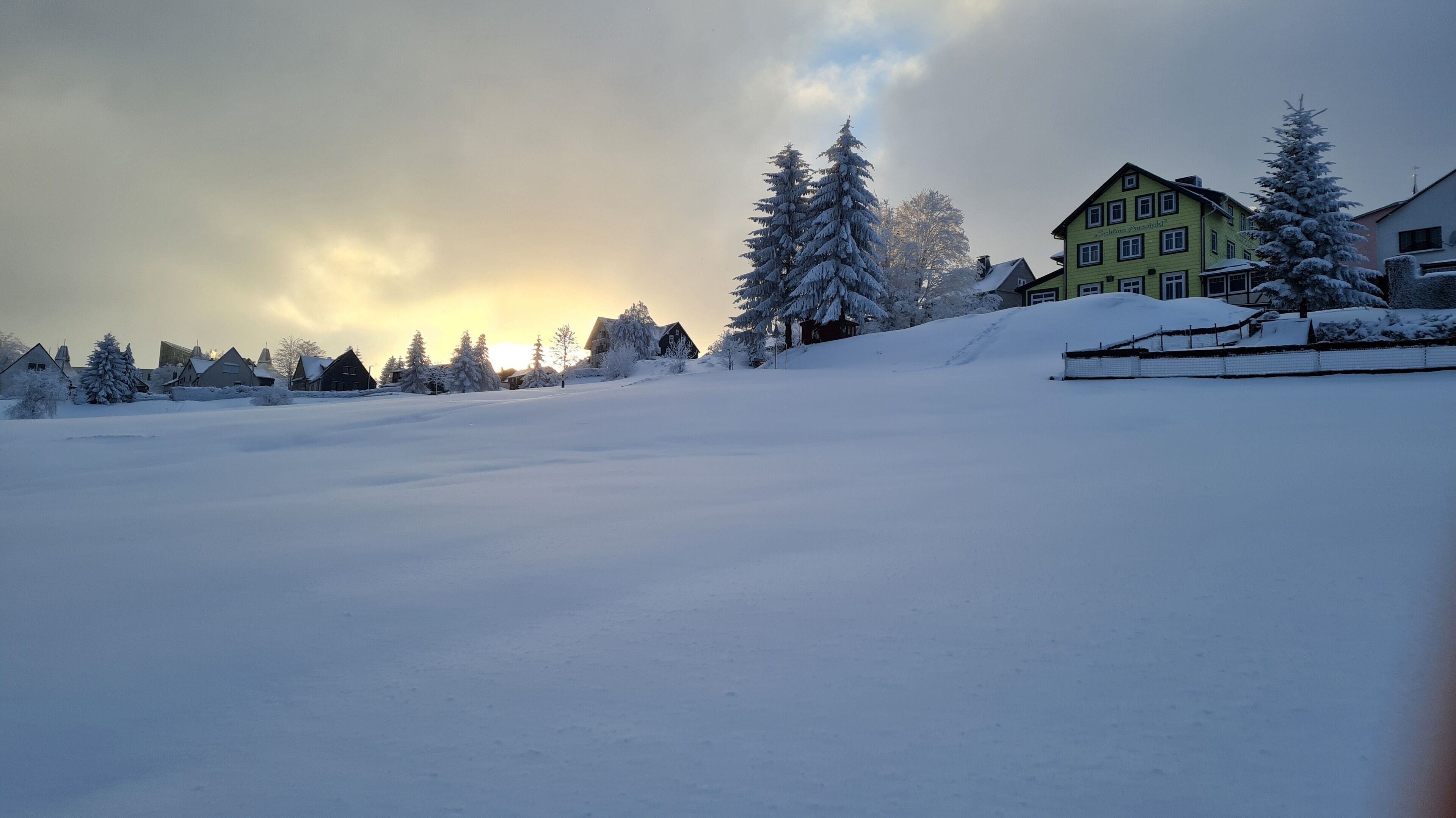 Paisagem coberta de neve com casas e árvores.