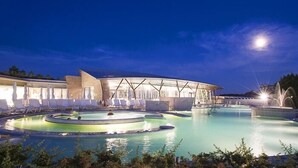 A modern hotel with a large outdoor pool area, including a circular water feature and lounge chairs. - Porsenna Resort (Castiglione del Lago)