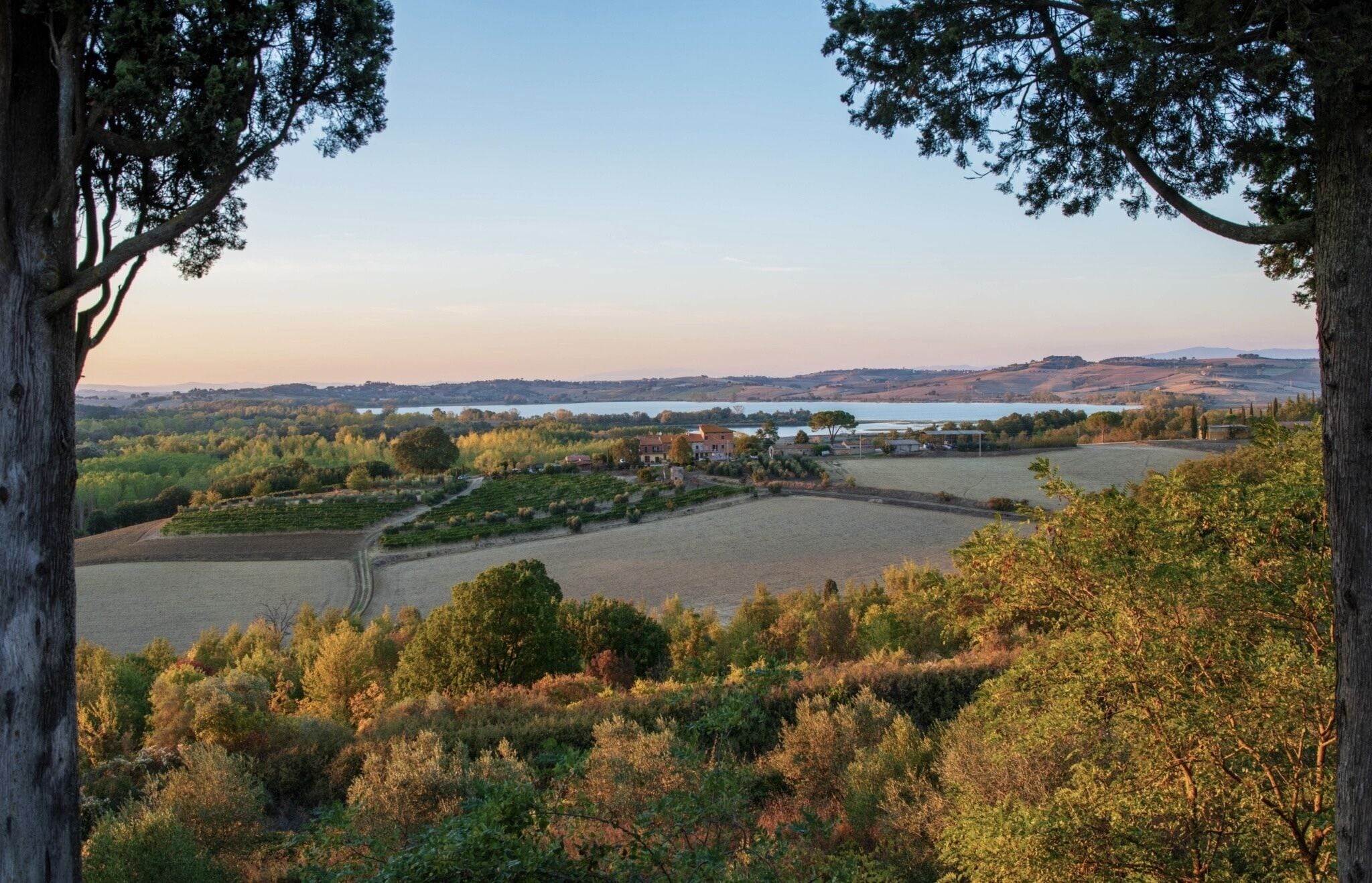 Un paisaje rural con una gran masa de agua, campos y edificios dispersos.